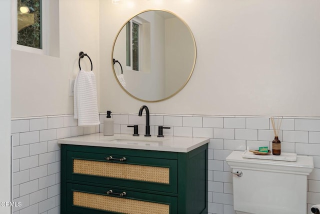 bathroom featuring vanity, toilet, and tile walls