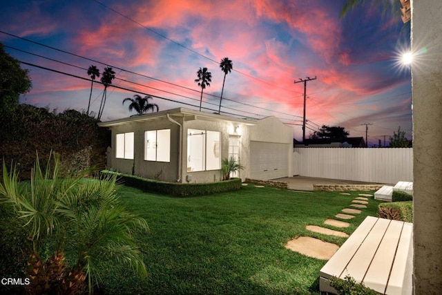 yard at dusk with a garage and a patio area