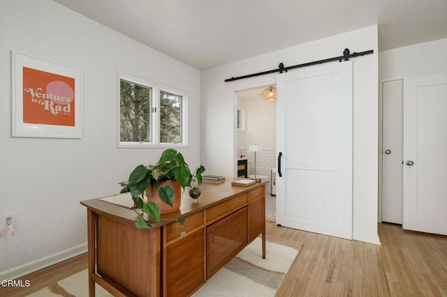 home office featuring a barn door and light hardwood / wood-style floors