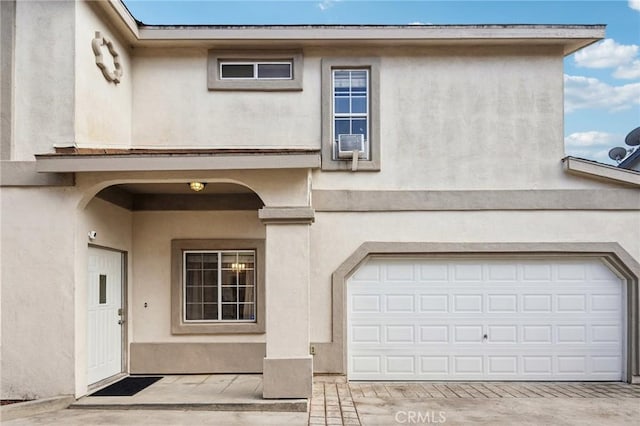 view of front of house with a garage, driveway, cooling unit, and stucco siding