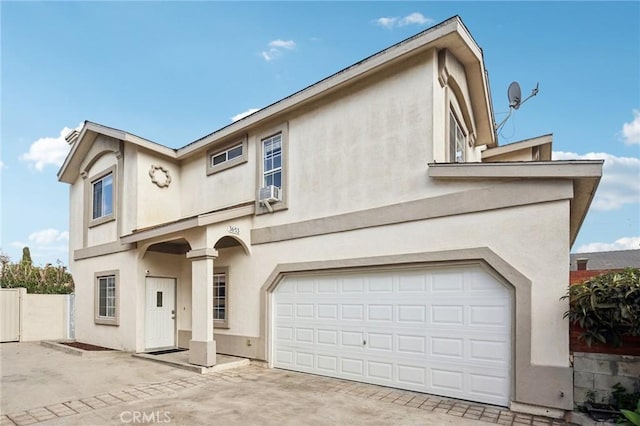 view of front of property with an attached garage, driveway, fence, and stucco siding