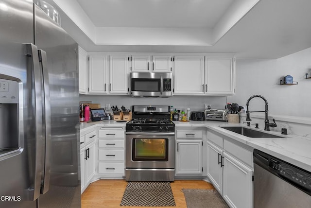 kitchen with light hardwood / wood-style floors, sink, white cabinetry, and appliances with stainless steel finishes