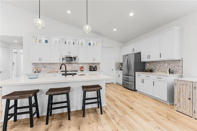 kitchen featuring white cabinetry, appliances with stainless steel finishes, vaulted ceiling, and pendant lighting