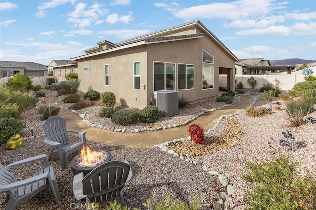 rear view of house featuring cooling unit and a fire pit