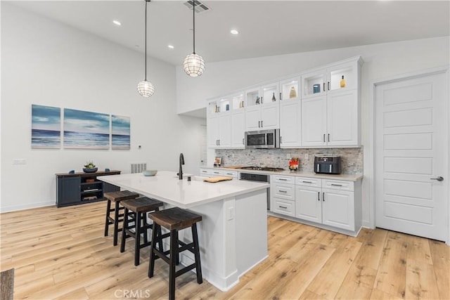 kitchen featuring lofted ceiling, tasteful backsplash, white cabinets, and appliances with stainless steel finishes