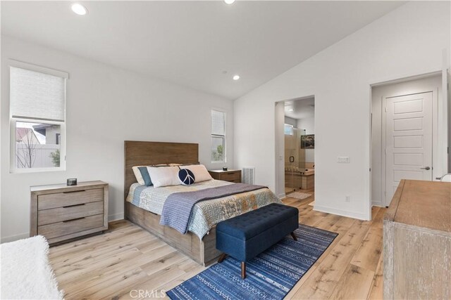 bedroom with lofted ceiling, ensuite bathroom, and light wood-type flooring