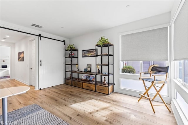 sitting room with a barn door and light hardwood / wood-style floors