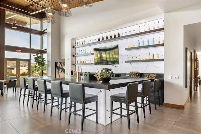 bar with french doors, tile patterned floors, and a high ceiling