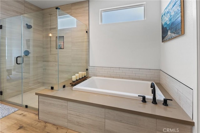 bathroom with independent shower and bath and hardwood / wood-style floors