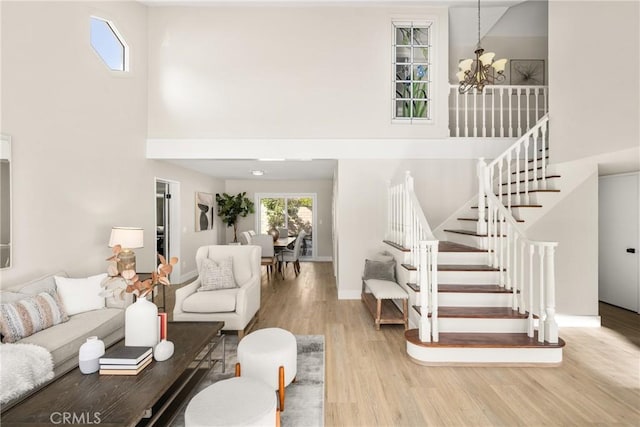 living room featuring light hardwood / wood-style floors, a towering ceiling, and an inviting chandelier