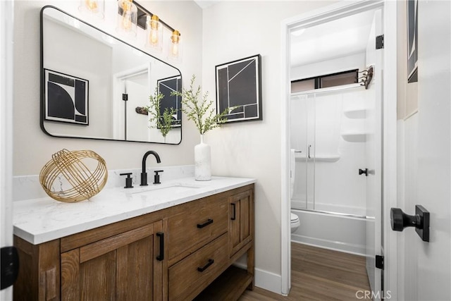 full bathroom featuring combined bath / shower with glass door, vanity, wood-type flooring, and toilet