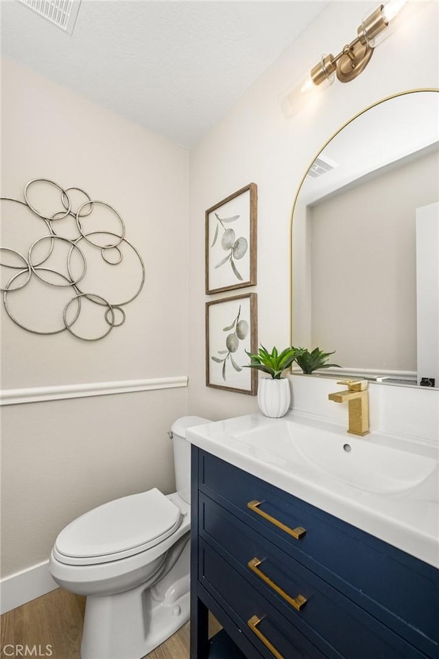 bathroom featuring toilet, vanity, and wood-type flooring