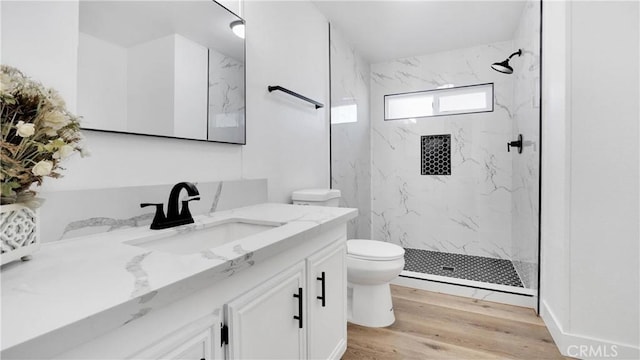 bathroom featuring toilet, vanity, a tile shower, and hardwood / wood-style flooring