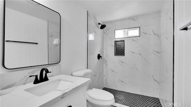 bathroom featuring toilet, vanity, and a tile shower