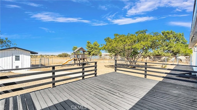 wooden deck featuring a playground and an outbuilding