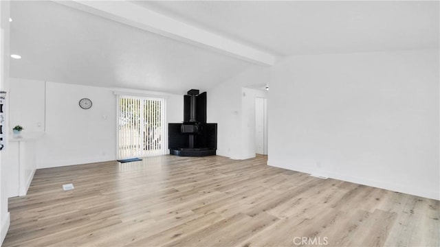 unfurnished living room featuring light hardwood / wood-style floors, a wood stove, and vaulted ceiling with beams