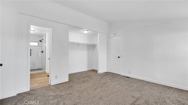 unfurnished bedroom featuring ensuite bathroom, a closet, carpet, and lofted ceiling