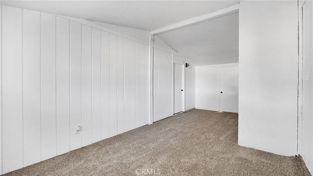 bonus room with carpet flooring, vaulted ceiling with beams, and wooden walls