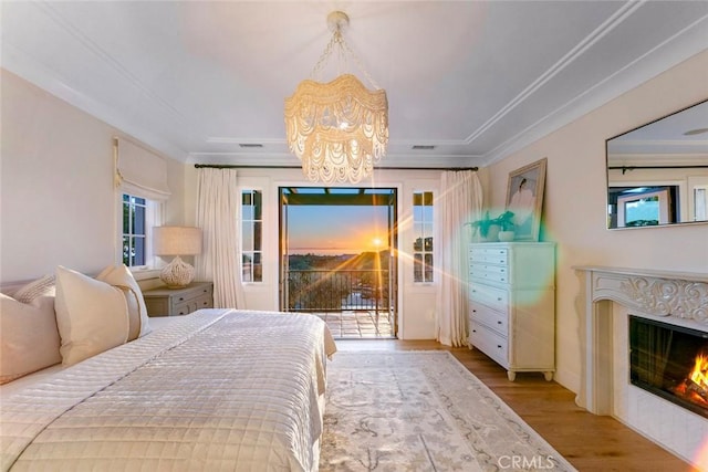 bedroom featuring light wood-type flooring, an inviting chandelier, ornamental molding, and access to outside