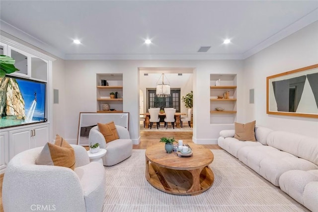 living room featuring built in shelves, ornamental molding, and hardwood / wood-style flooring