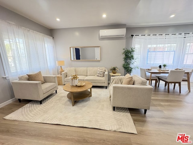 living room with a wealth of natural light, light hardwood / wood-style flooring, and a wall mounted AC