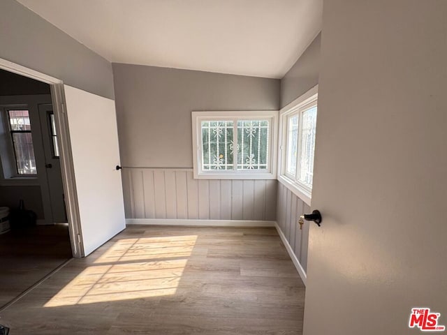 spare room featuring lofted ceiling and light hardwood / wood-style flooring