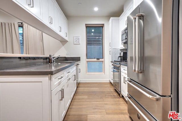 kitchen featuring light wood-type flooring, high quality appliances, white cabinets, and sink