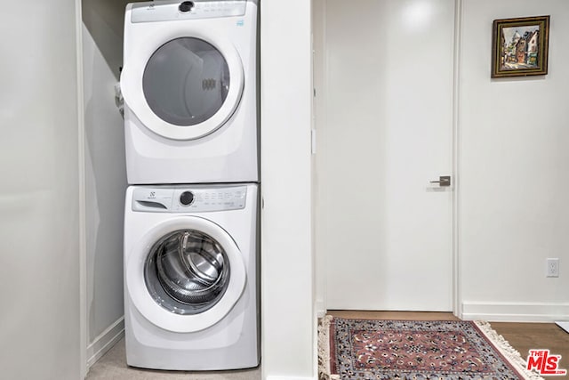 laundry area with stacked washing maching and dryer and hardwood / wood-style flooring