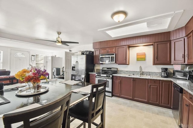 kitchen featuring sink, light stone countertops, ceiling fan, and appliances with stainless steel finishes