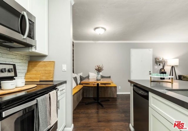 kitchen with decorative backsplash, white cabinetry, dark wood-type flooring, ornamental molding, and stainless steel appliances