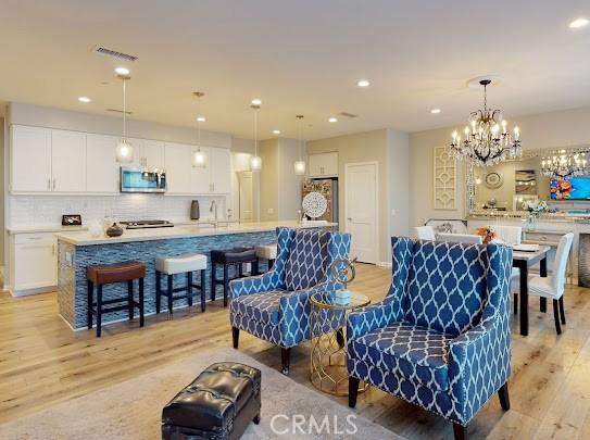 living room with sink, light hardwood / wood-style flooring, and a chandelier