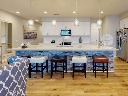 bar with sink, pendant lighting, appliances with stainless steel finishes, and white cabinets