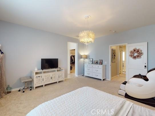 bedroom with a spacious closet, a closet, carpet, and a notable chandelier