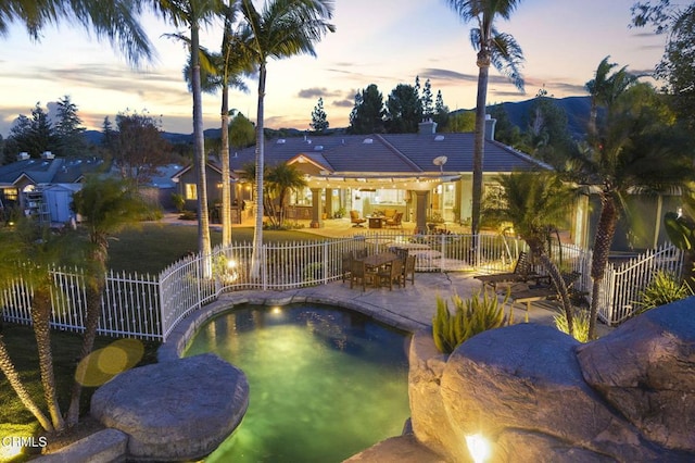 pool at dusk featuring a mountain view and a patio