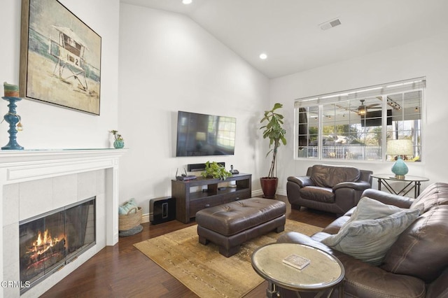 living room with a tile fireplace, vaulted ceiling, and dark hardwood / wood-style flooring