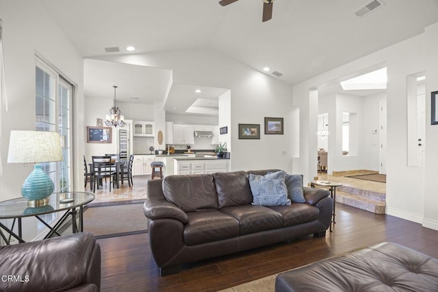 living room featuring a healthy amount of sunlight, ceiling fan with notable chandelier, dark hardwood / wood-style floors, and lofted ceiling