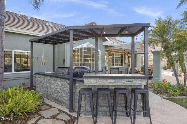 view of patio / terrace with a bar, an outdoor kitchen, grilling area, and a pergola