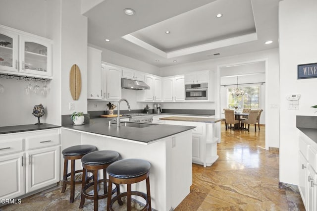 kitchen featuring kitchen peninsula, white cabinets, oven, and a tray ceiling