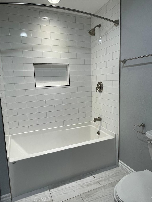 bathroom featuring toilet and tiled shower / bath combo