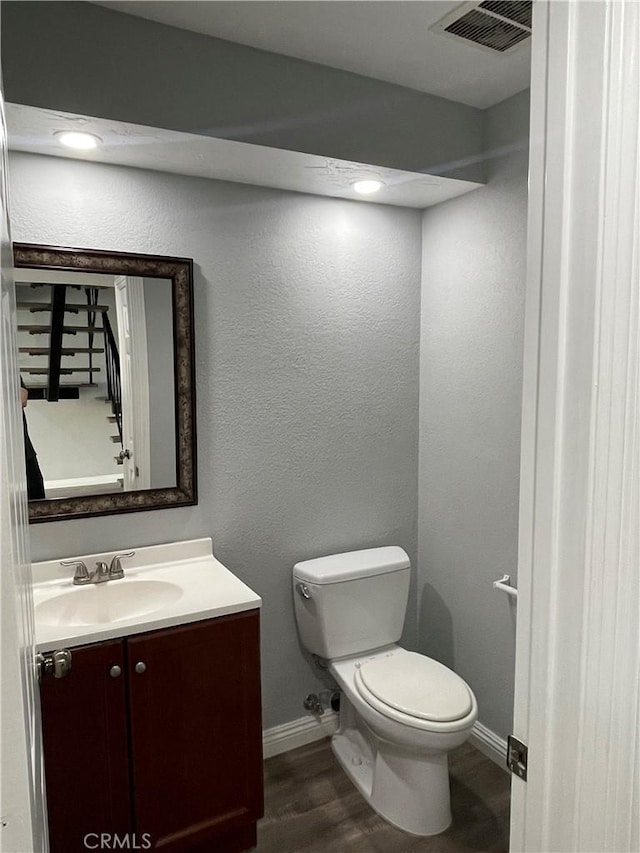 bathroom featuring toilet, vanity, and wood-type flooring