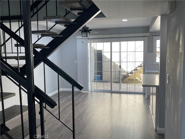 stairway with ceiling fan, wood-type flooring, and plenty of natural light