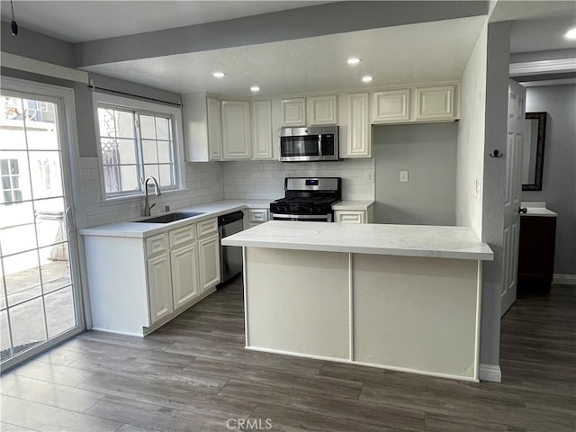 kitchen featuring light stone countertops, white cabinets, stainless steel appliances, decorative backsplash, and sink