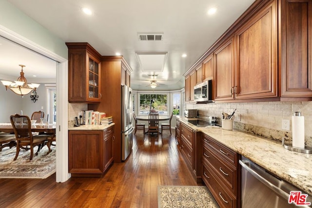 kitchen with appliances with stainless steel finishes, pendant lighting, dark hardwood / wood-style flooring, and tasteful backsplash