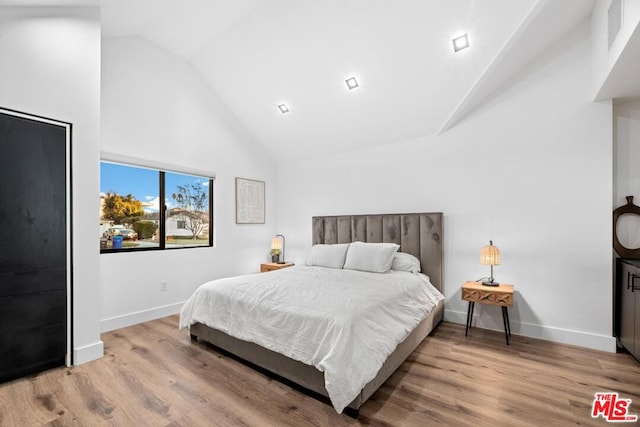 bedroom with light hardwood / wood-style flooring and high vaulted ceiling