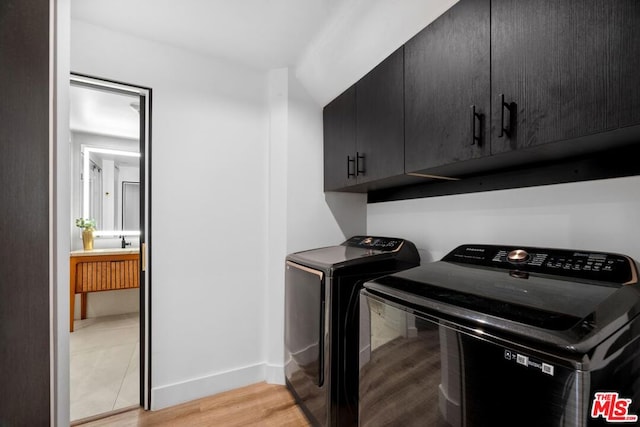 laundry area featuring light hardwood / wood-style flooring, washer and dryer, and cabinets