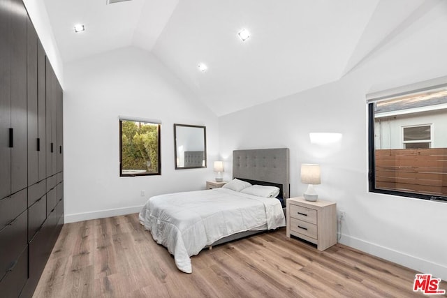 bedroom featuring light wood-type flooring and vaulted ceiling