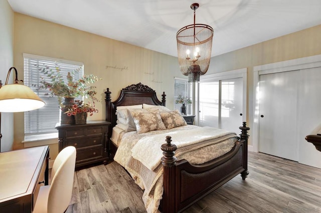 bedroom featuring a chandelier, light hardwood / wood-style floors, and multiple windows