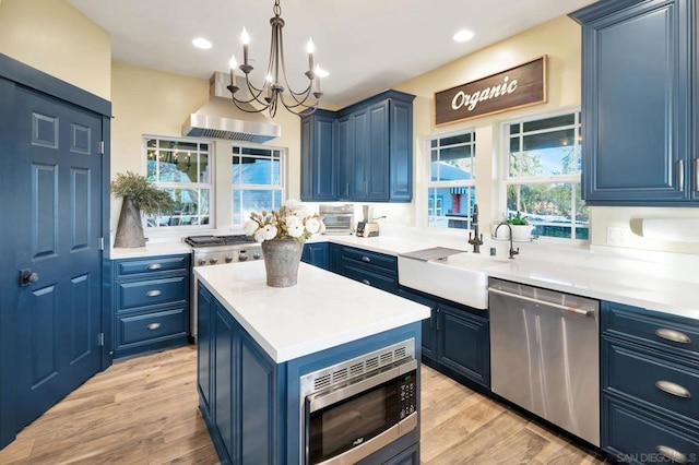 kitchen with sink, blue cabinetry, a center island, range hood, and stainless steel appliances