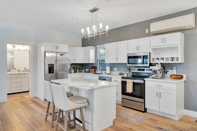 kitchen featuring white cabinets, stainless steel appliances, a kitchen island, and a wall mounted air conditioner