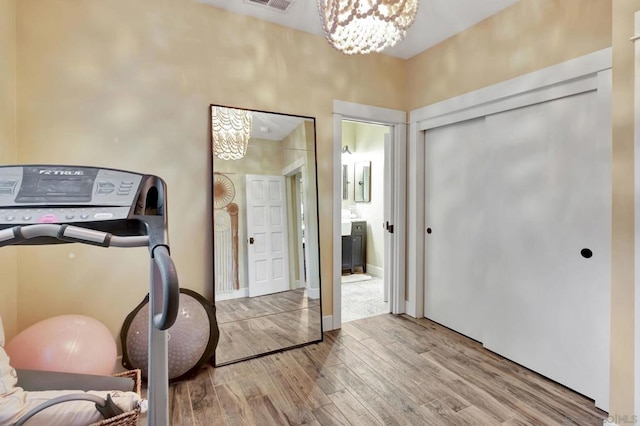 exercise area featuring a notable chandelier and light hardwood / wood-style flooring